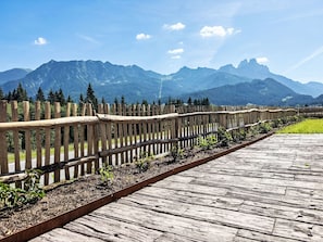 Um deck de madeira com guarda-corpo de metal, que dá para uma paisagem montanhosa.