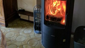 En vedeldad kamin med synliga lågor, ett träskåp och ett klinkergolv.