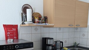 Een moderne keuken met houten kastjes, een inbouwfornuis, een koffiezetapparaat en een waterkoker.