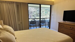 Ein Hotelzimmer mit Bett, einem Schminktisch, einem Fernseher und einem Balkon mit Stühlen.