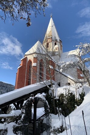 A snow-covered church with a prominent bell tower and a stone bridge in the foreground. - Chalet Elsa Murau by Interhome (Murau)