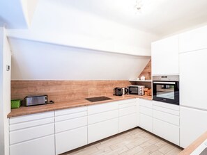 Una cocina moderna con armarios blancos, encimera de madera, horno empotrado y microondas.