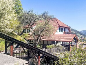 A traditional chalet with a red-tiled roof, surrounded by lush greenery and a wooden bridge. - Apartment  by Interhome (Murau)