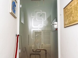 A hallway with a glass door, a red towel, and a framed picture on the wall. - Apartment  by Interhome (Murau)