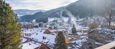 A town with buildings, a river, and snow-covered hills.