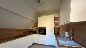 Une cuisine moderne avec des armoires blanches, un plan de travail en bois, un four encastré et un évier.