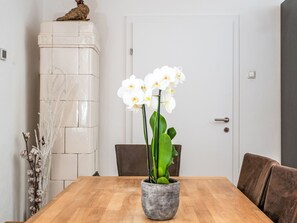 A dining table with a potted orchid, a white cabinet, and a brown chair. - Apartment  by Interhome (Murau)