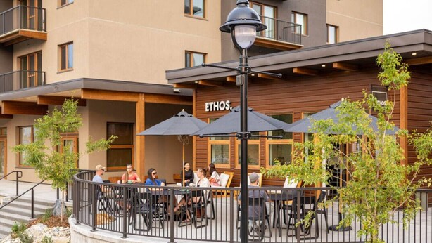Un espace extérieur aménagé avec des tables et des parasols au restaurant ETHOS.
