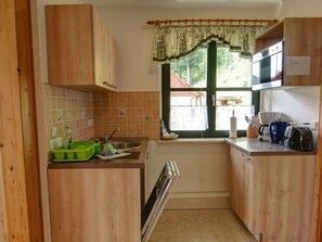 Een koelkast, een magnetron, een vaatwasser, kookgerei, borden en bestek