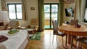 Et hotelværelse med en seng, to lænestole, et spisebord og et fjernsyn.