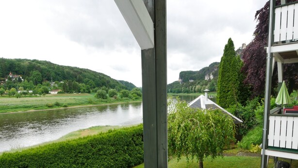 A view from a balcony overlooking a river, with a house and greenery in the background. - Wohnung Barbarine by Interhome (Königstein)