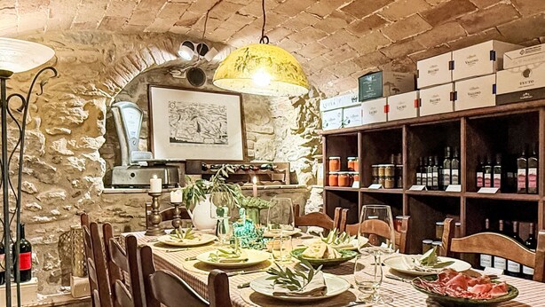 A dining area with a brick wall, a table set for four, and a wine rack in the background. - La Cisterna by Interhome (Volterra)