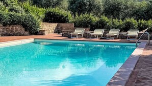 A rectangular swimming pool with clear blue water, surrounded by a stone wall and a tiled deck. - La Cisterna by Interhome (Volterra)