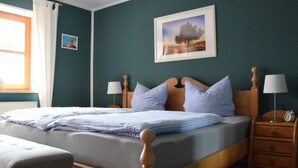 Une chambre à coucher avec un lit en bois, deux tables de chevet avec des lampes, un banc et une fenêtre avec des rideaux.