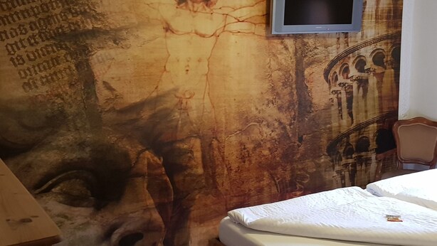 A bedroom with a mural on the wall, a television mounted above the bed, and a wooden chair. - Elbufer 4C by Interhome (Marschacht)