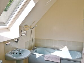 Une salle de bain avec un puits de lumière, un lavabo, une baignoire et un porte-serviettes.
