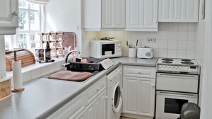 Una cucina moderna con mobili bianchi, un forno a microonde, un tostapane, un piano cottura e una lavatrice.