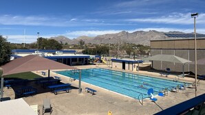En swimmingpool med blå linedelere, omgivet af blå bænke og liggestole.