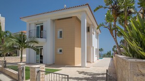 Un bâtiment moderne à deux étages, doté d’une façade beige et blanche, d’un balcon et d’une entrée sécurisée par un portail.