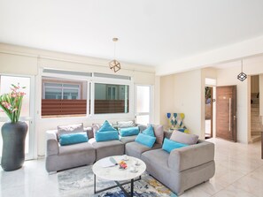 Ein modernes Wohnzimmer mit Ecksofa, Couchtisch und großem Fenster.