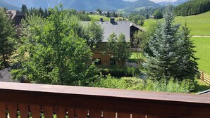 Blick auf Berge mit einem Haus, umgeben von viel Grün.