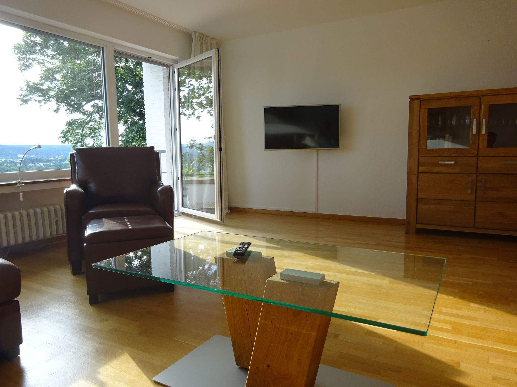 Un salon moderne avec une table basse en verre, un fauteuil en cuir et un meuble en bois.