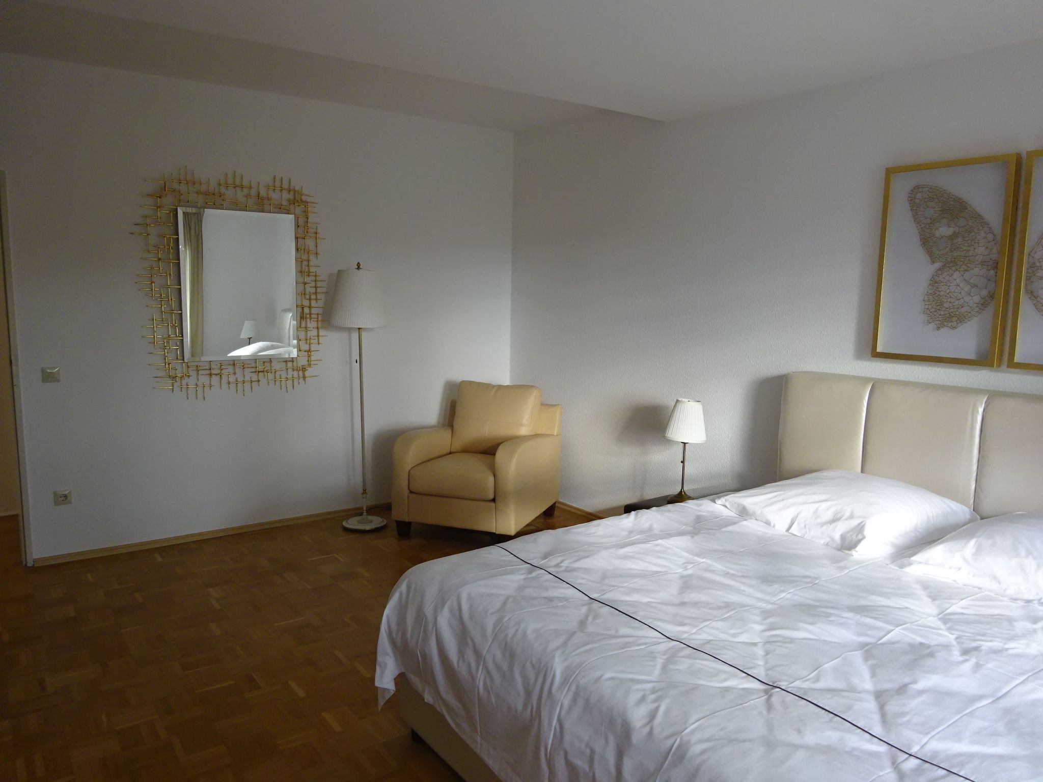 Ein Hotelzimmer mit Bett, Stuhl, Lampe und einem Wandspiegel.