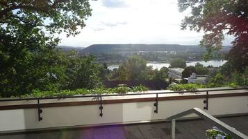 Ein Balkon mit Blick auf einen Fluss und sanfte Hügel in der Ferne.