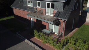 Una casa a due piani con un balcone, un garage e un piccolo giardino.