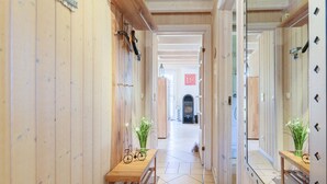 Ein hölzerner Flur mit einer Bank, einem Fahrrad und einem Spiegel an der Wand.