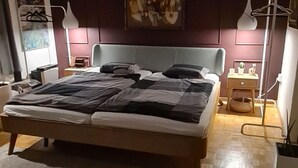 Une chambre à coucher moderne avec un grand lit, des tables de chevet, une lampe suspendue et un tableau au mur.