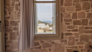 A stone wall with a window and a curtain.