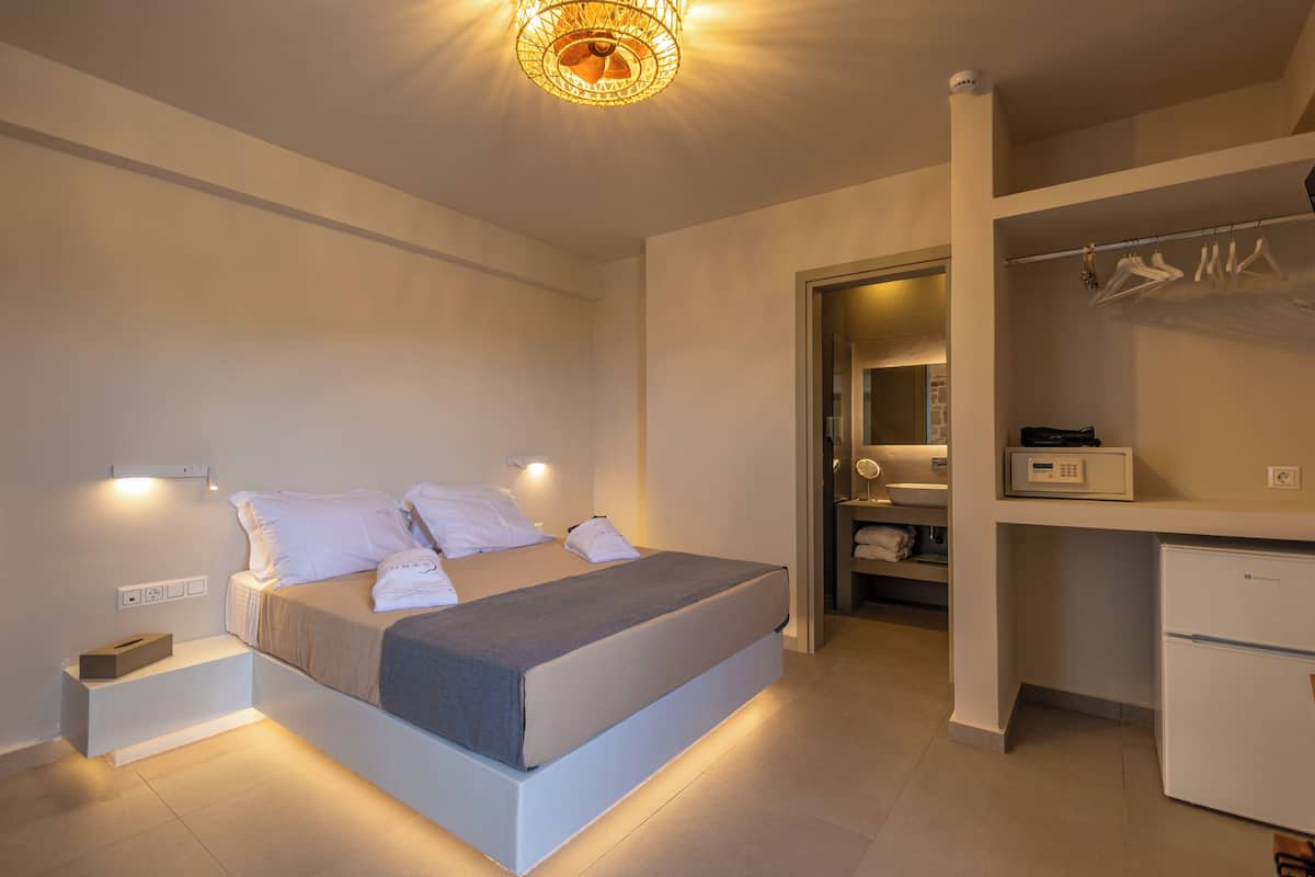 A modern bedroom with a bed, bedside tables, a wardrobe, and a desk.