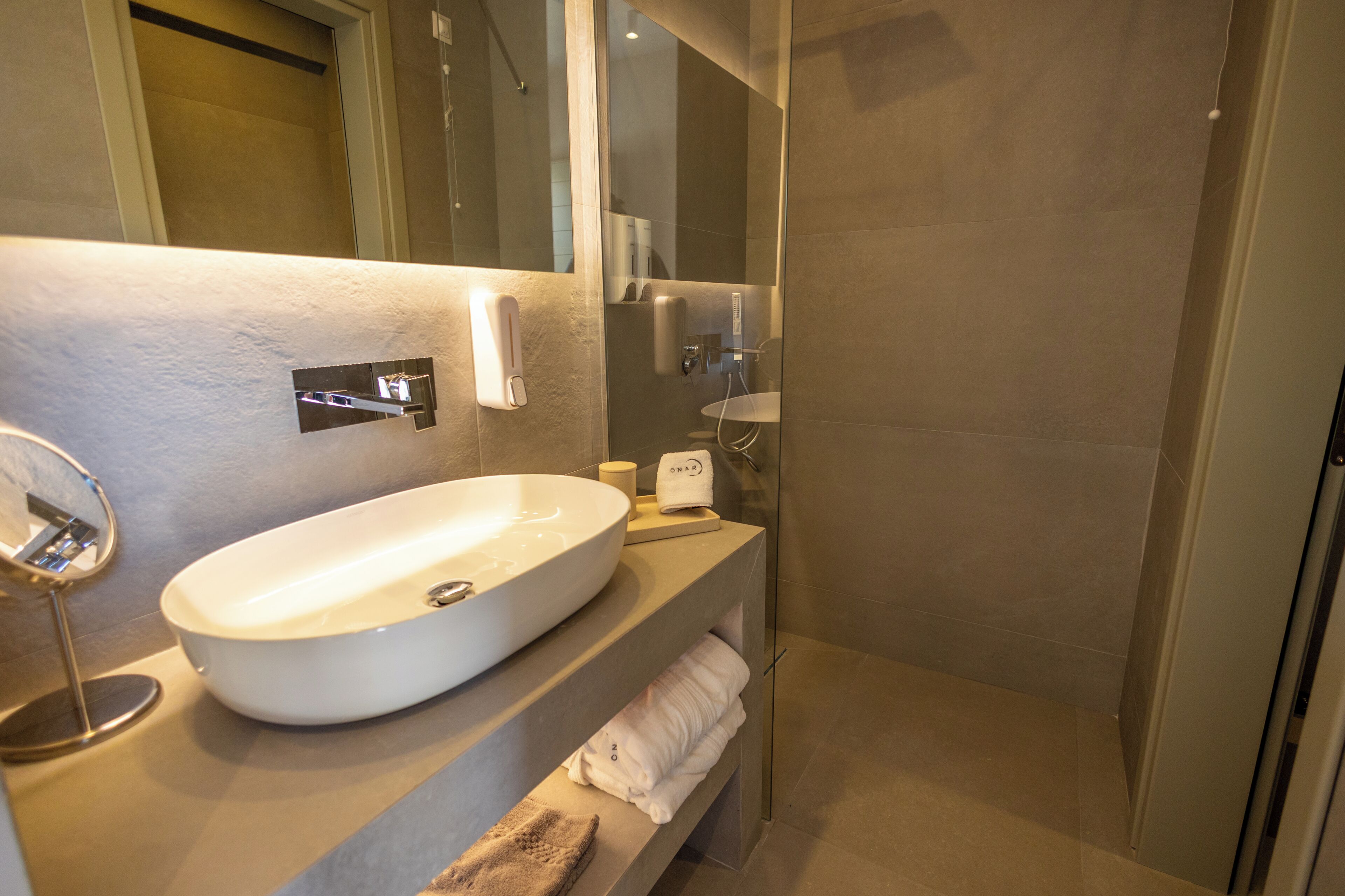 Un bagno moderno con un lavandino ovale ampio, uno specchio e un porta asciugamani.