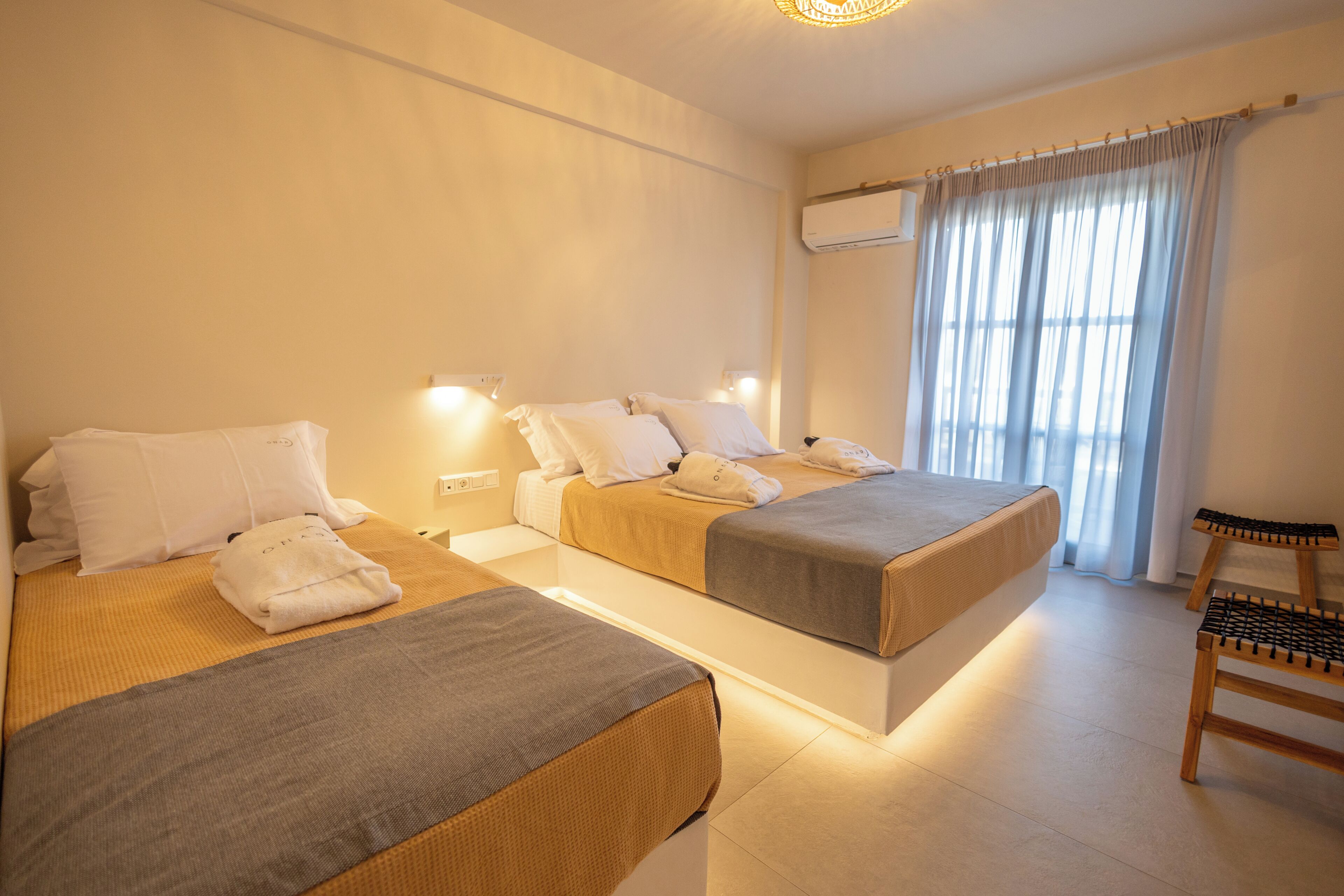 Ett hotellrum med två sängar, en trästol och ett fönster med gardiner.