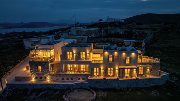 A modern house with multiple levels, a stone foundation, and a circular patio.