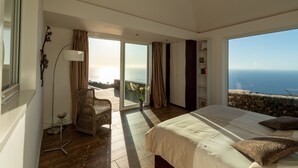 A bedroom with a large bed, a chair, a floor lamp, and a view of the ocean. - Moderne Architekten-Villa mit Infinity-Pool und Meerblick by Interhome (Puntagorda)