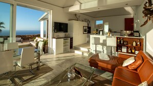 A modern living room with a glass coffee table, a leather sofa, and a dining area with a glass table. - Moderne Architekten-Villa mit Infinity-Pool und Meerblick by Interhome (Puntagorda)