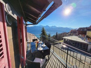 Un balcone con un tavolo apparecchiato per due, con vista su un paesaggio montano.