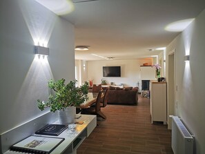 A modern living room with a sofa, a coffee table, and a potted plant. There is a flat-screen TV mounted on the wall and a fireplace in the background. - Oebel in Brüggen by Interhome (Brüggen)