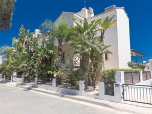 A modern two-story building with a white facade, surrounded by lush tropical plants and a gated entrance. - Ferienvilla für 10 Personen in Protaras by Interhome (Protaras)