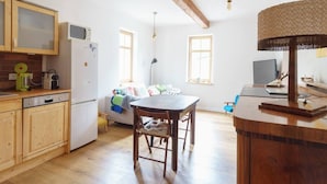 A compact kitchen with wooden cabinets, a dining table, and a lamp. - Komfortable Ferienwohnung in Paulinzella mit Großem Garten by Interhome (Königsee)