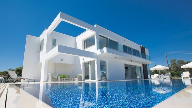 Una moderna casa a due piani con una piscina di fronte.
