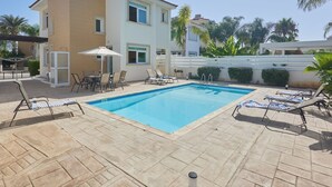 A two-story building with a swimming pool, outdoor seating, and palm trees. - Hübsche Villa mit 3 Schlafzimmern und privatem Pool by Interhome (Protaras)