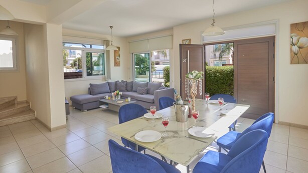 A spacious living area with a sofa set, a dining table with chairs, and a view of the outdoors through large windows. - Hübsche Villa mit 3 Schlafzimmern und privatem Pool by Interhome (Protaras)
