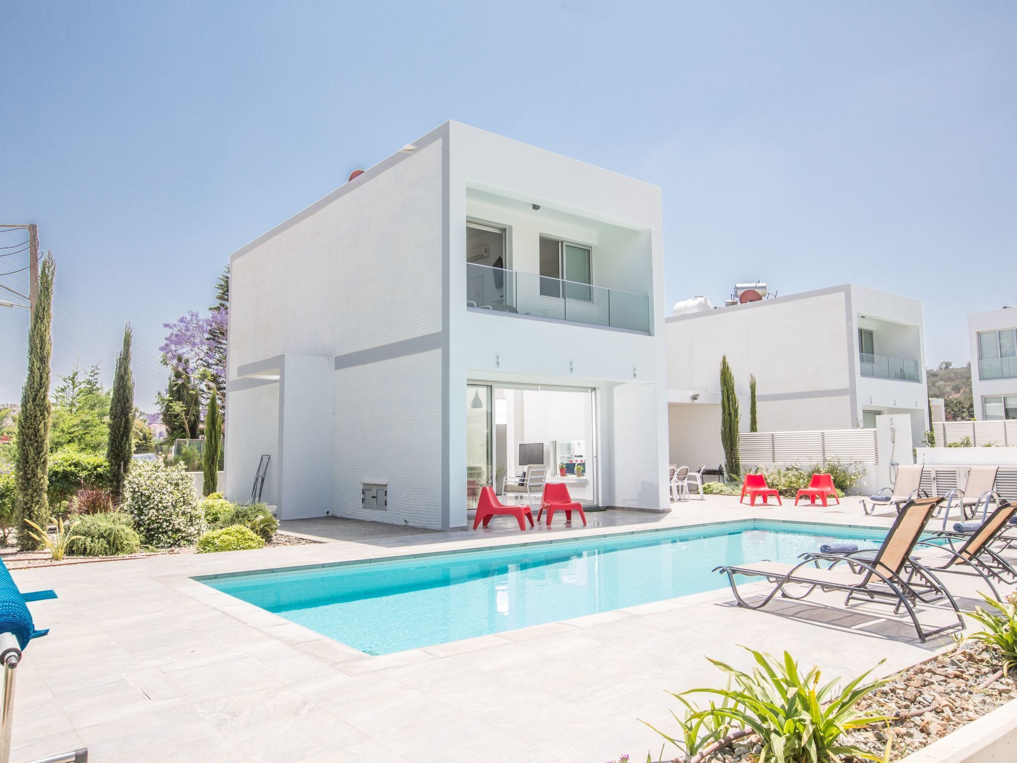 A modern two-story building with a swimming pool, outdoor seating, and a well-maintained garden.