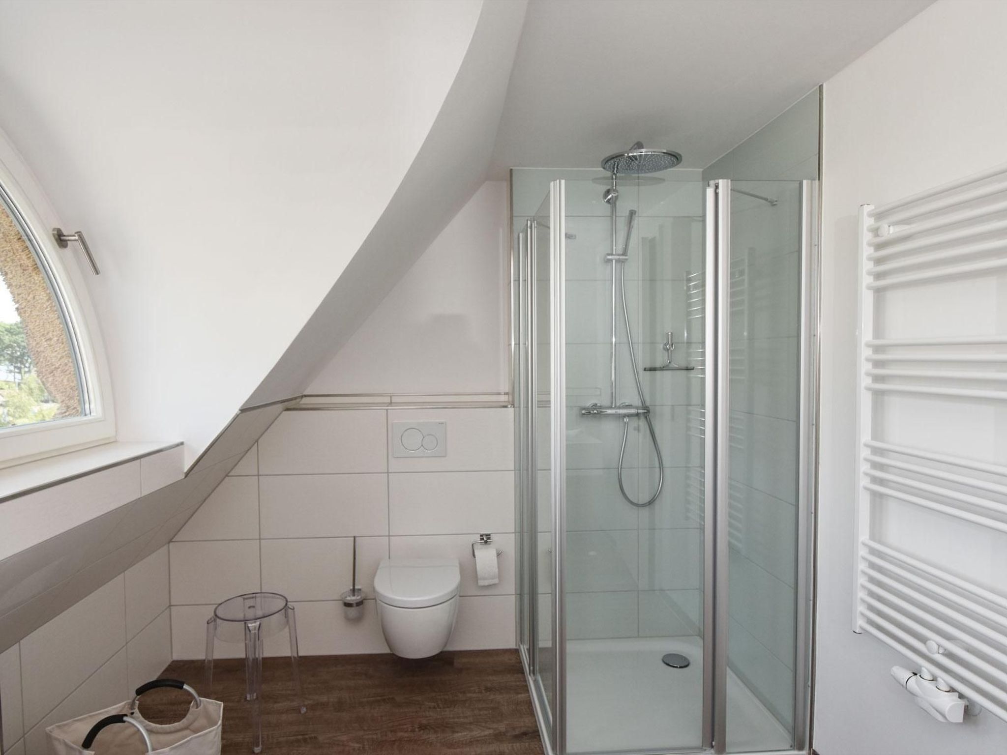 Une salle de bain moderne avec une douche à parois de verre, des toilettes et une petite table.
