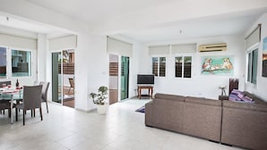 Amplia sala de estar con una mesa de comedor, sillas, un sofá y un televisor.