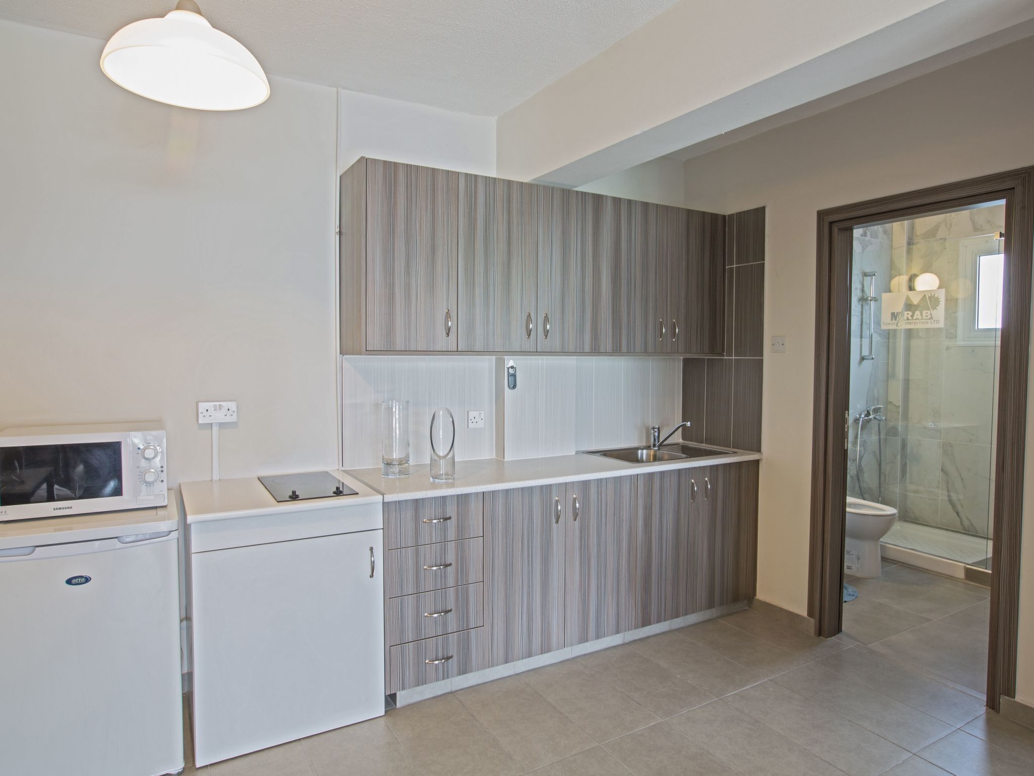 A modern kitchen with grey cabinets, a built-in microwave, and a sink.