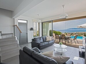 Ein modernes Wohnzimmer mit einer Couch, einem Couchtisch und Blick aufs Meer.